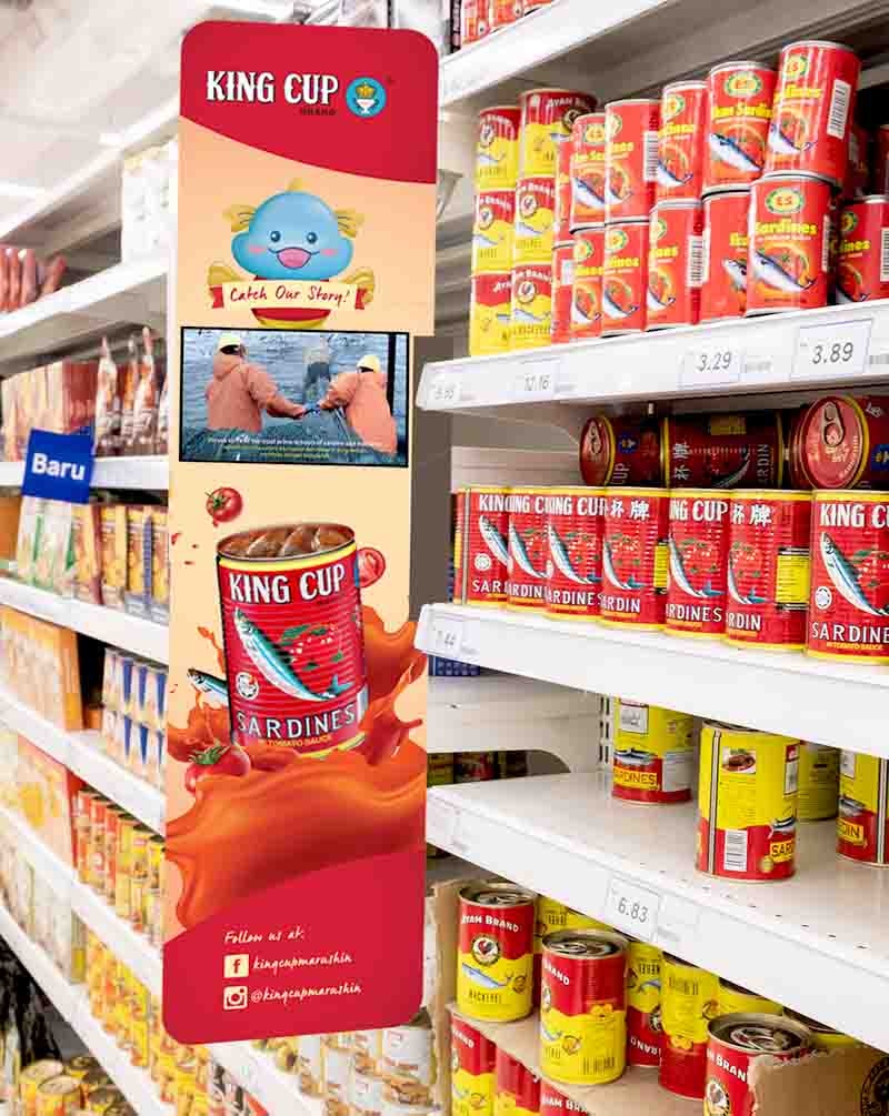 An aisle banner show KING CUP Sardine advertisement with the aisle filled with KING CUP Sardines along with other sardine cans from various others brands