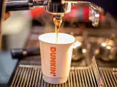 Dunkin’ coffee cup is being filled with coffee from a coffee machine