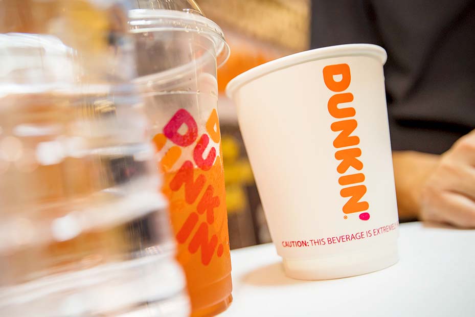 White plastic cup and larger transparent cup with DUNKIN’ written in orange on it; A DUNKIN’ GOOD TIME written over the image