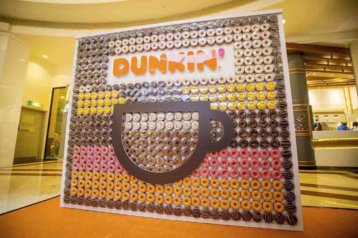 Dunkin’ branded art installation with Dunkin’ Donuts arranged within its transparent wall and large coffee symbol on it